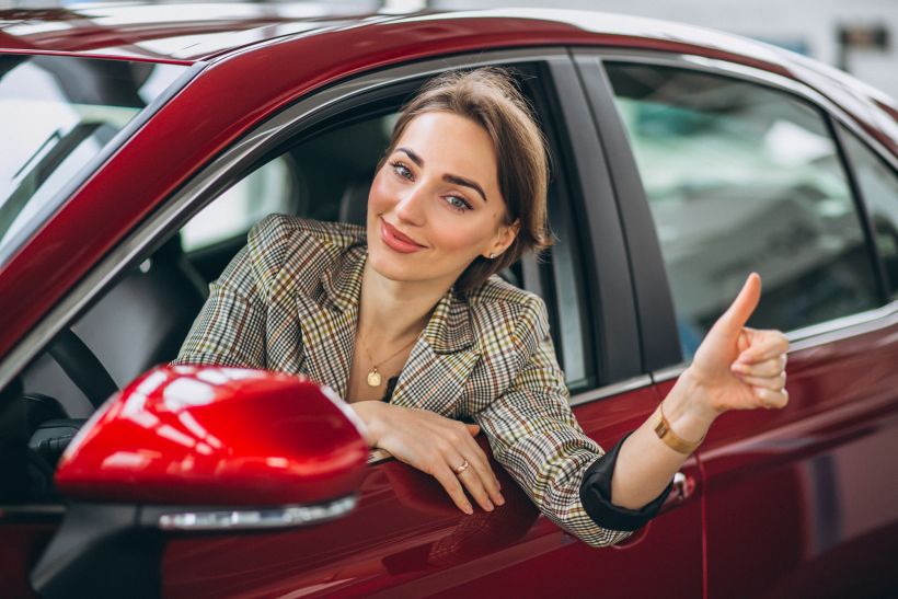 Woman sitting i car in a car showrrom.