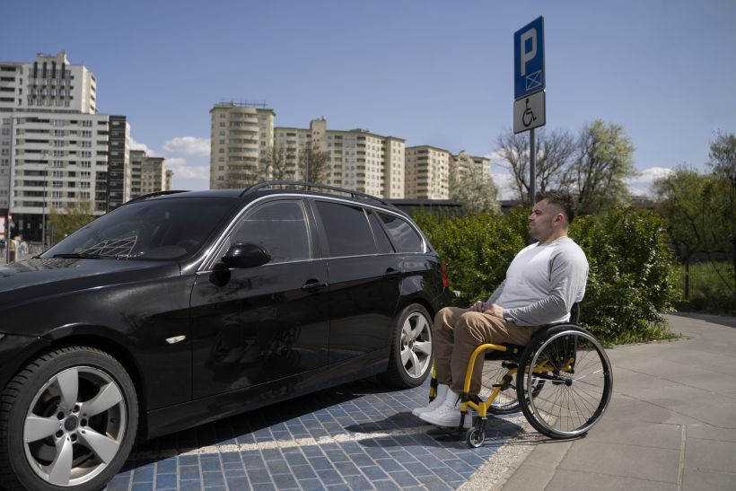 Side view man in wheelchair near car.