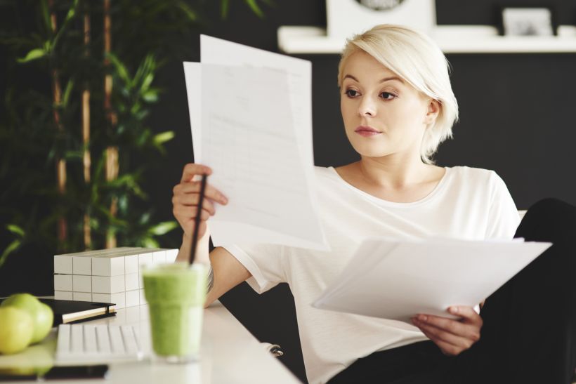 Concentrated businesswoman comparing documents at office.