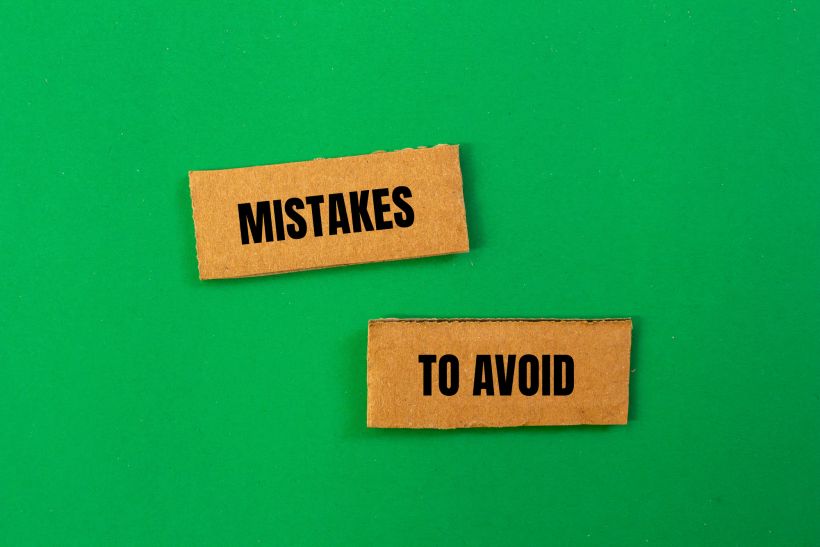 Mistakes to avoid message written on ripped cardboard paper pieces with green background conceptual mistakes to avoid.