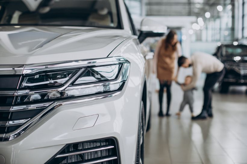 Family with baby girl choosing a car in a car salon.
