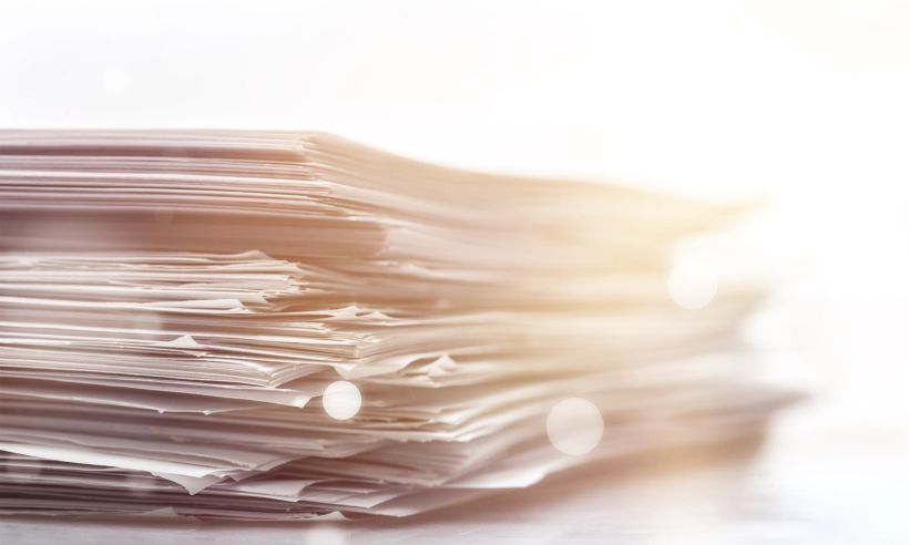 Pile of paper documents on background, close up.