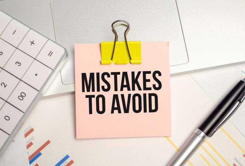 Business concept text mistakes to avoid on notepad and pen.