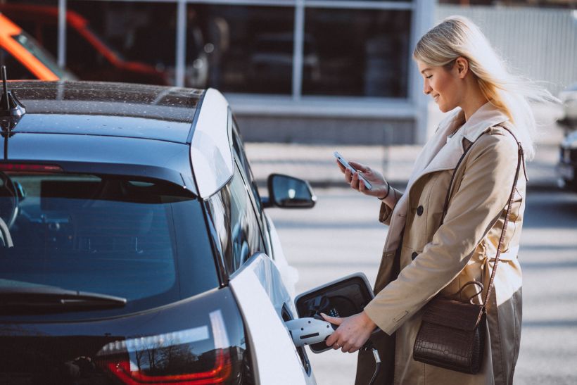 Mujer cargando un coche eléctrico en una estación de servicio eléctrica.