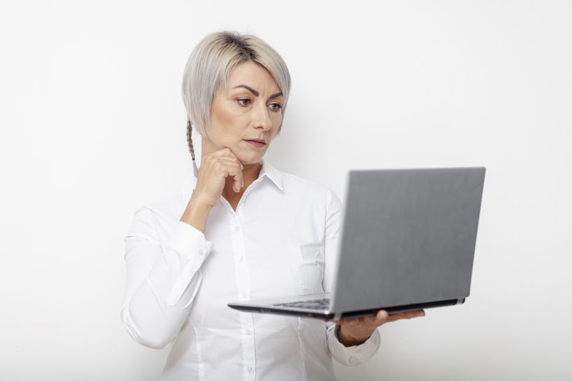 Vista frontal de una mujer de negocios sosteniendo un ordenador portátil y pensando.