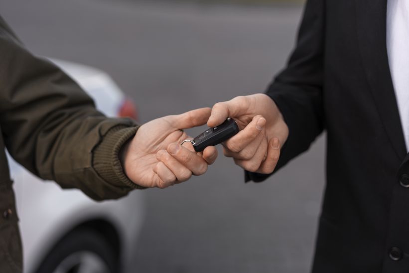 Manos en &aacute;ngulo elevado sosteniendo la llave del coche.