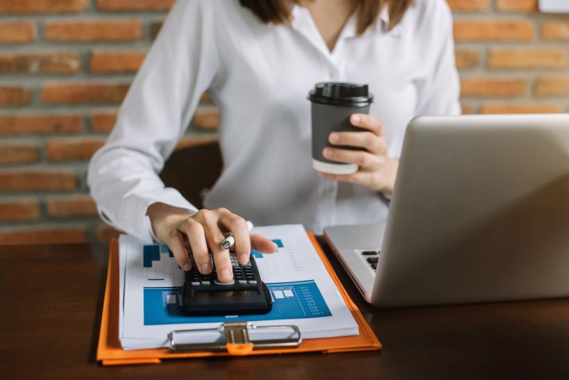 Mujer trabajando en una oficina con una calculadora para calcular impuestos.