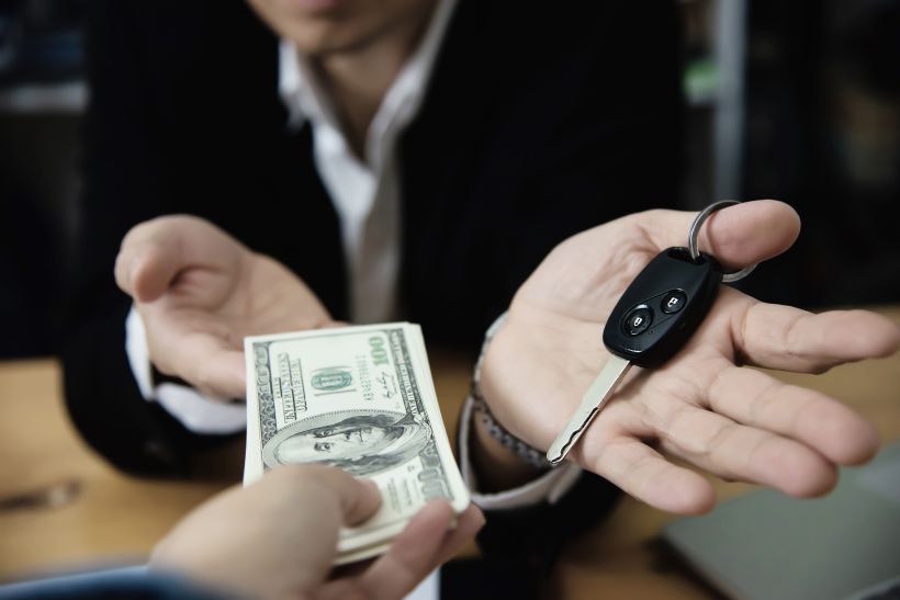 Un hombre de negocios muestra billetes de banco, hace un plan financiero e invita a gente a vender o comprar coches.