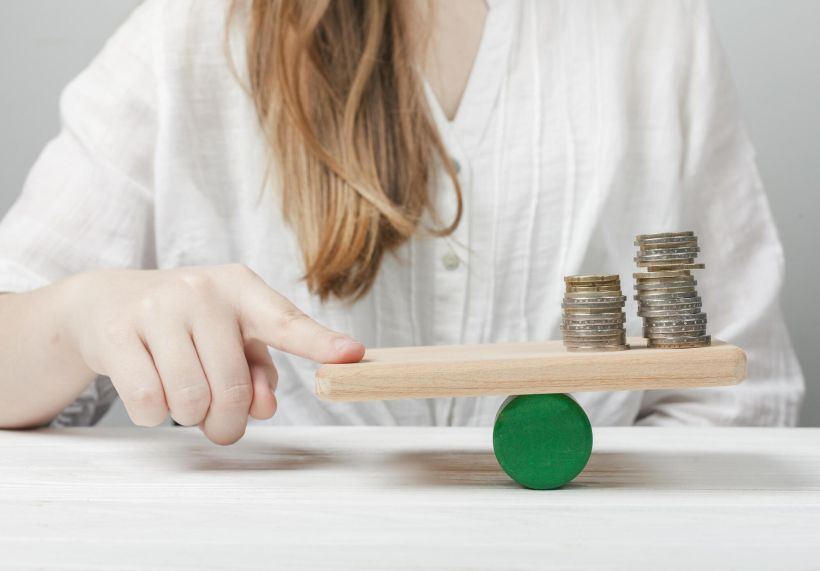 Mujer sosteniendo su dedo en equilibrio con las monedas.