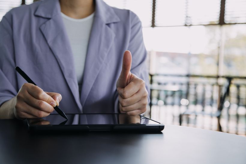 Mujer de negocios asi&aacute;tica utilizando una calculadora y un ordenador port&aacute;til para realizar c&aacute;lculos financieros.