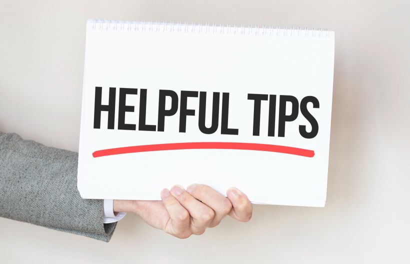 A businessman holds a card with the text “HELPFUL TIPS”