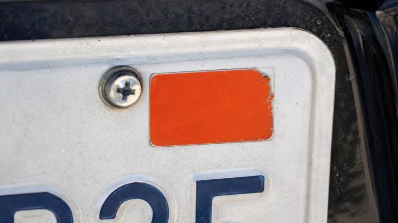 An orange tag on a license plate shows one of the many California registration sticker colors