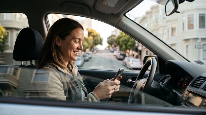 A smiling person sitting in a parked car on a San Francisco street