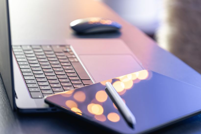 Digital tablet stylus pen and laptop on the desktop close up.